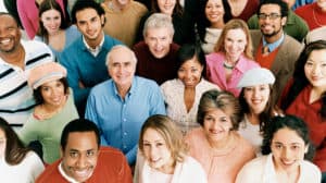 Photographed from above, a large group of smiling people looking up at the camera