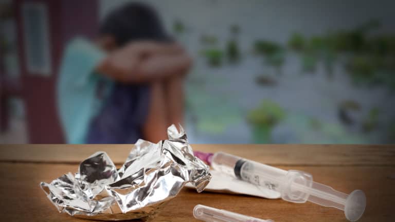 Opioid Syringe On A Table With A Man Out-Of-Focus in the background