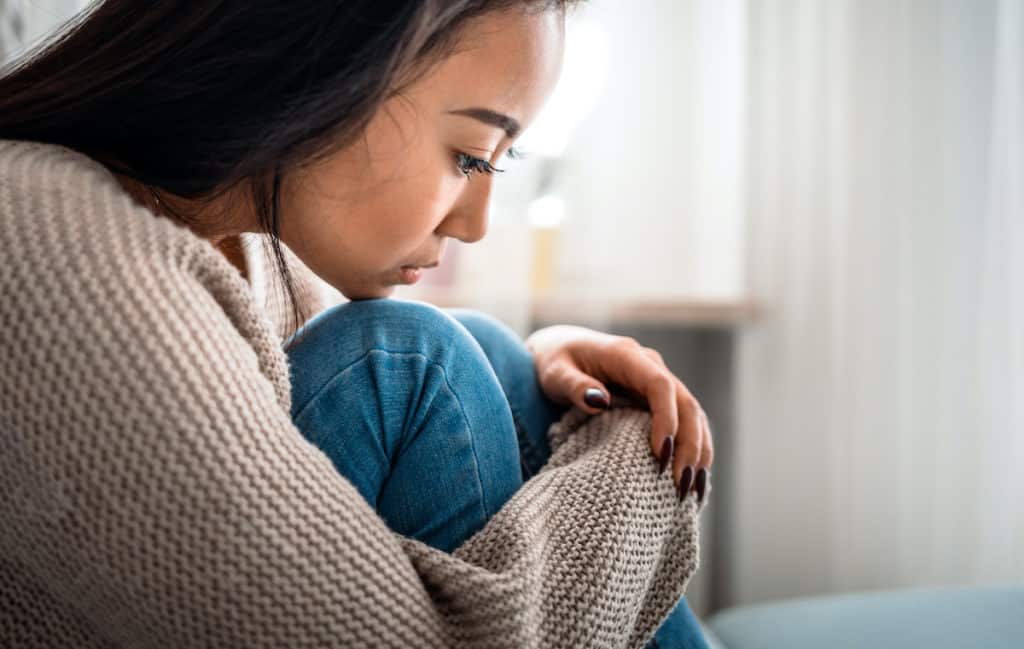 a teenager pregnant child sits alone in need of support.