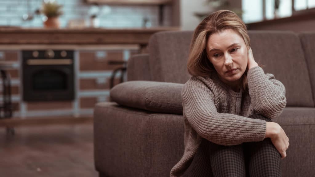 a sad-faced woman sits on the floor