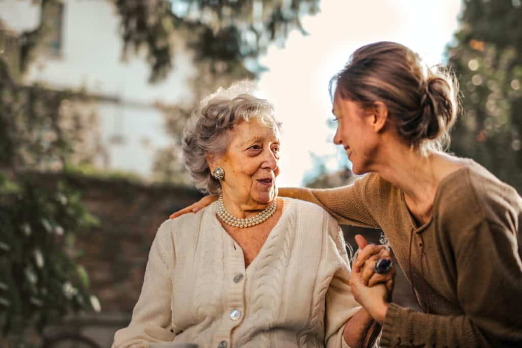 Joyful adult daughter greeting her happy, senior mother who's in a wheelchair