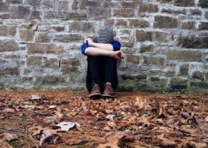 Person leaning over against a wall head in hands