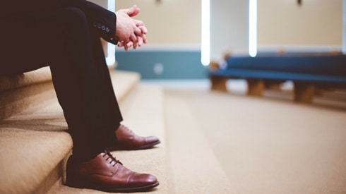 man in suit sitting in a church ready to defend the faith