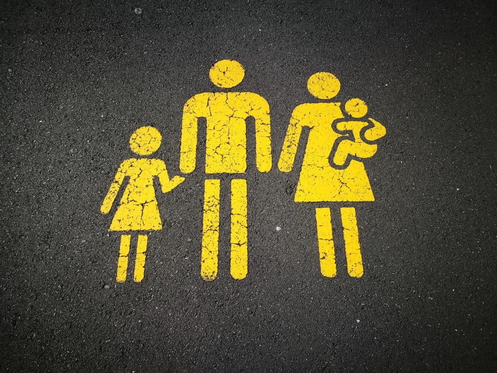 Yellow family structure icons portrayed on pavement with dark background.