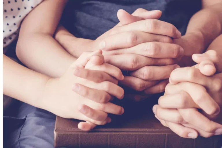 image of three young hands clasped together in prayer.