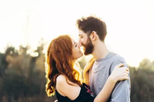 A photo of a young couple embracing each other, standing with their faces close as if they're about to kiss in an intimate moment. It is possible to enjoy a satisfying sex life with your spouse. It takes some planning and a deliberate focus, but the results are worth it.